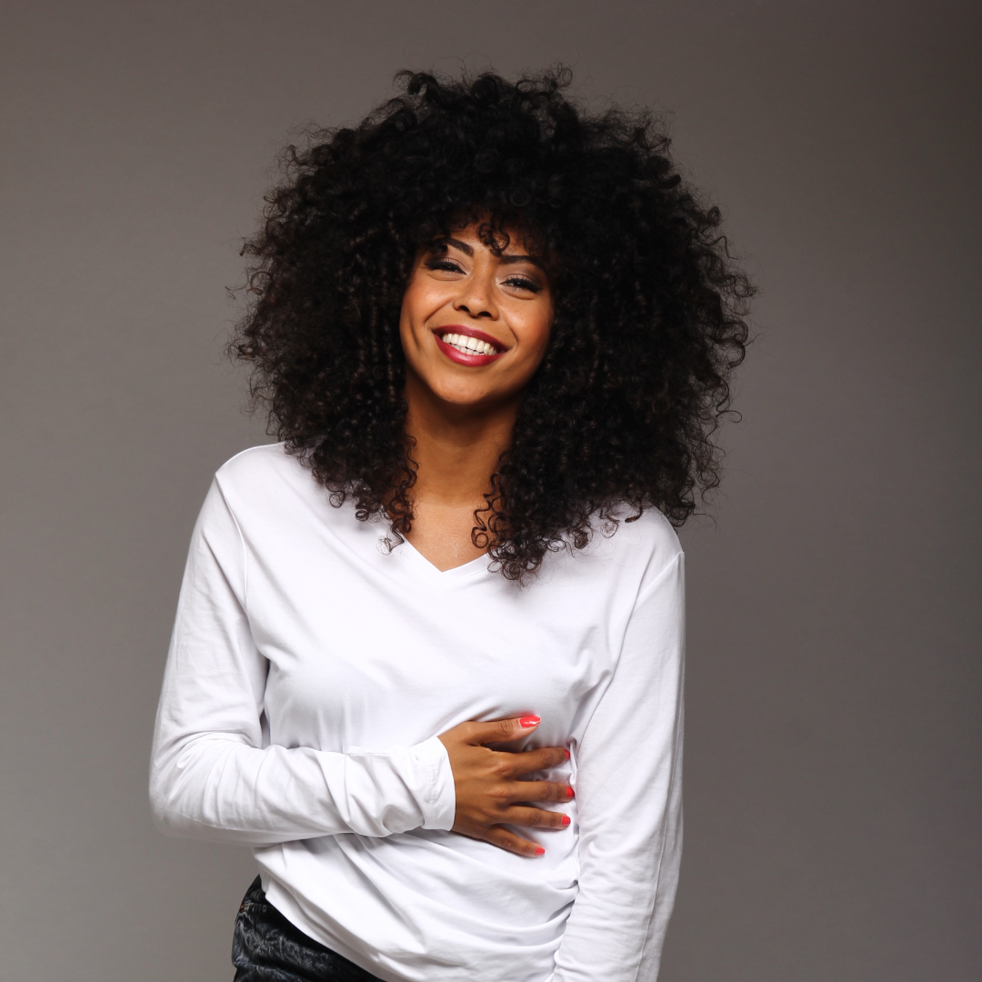 smiling lady with afro kinky curly hair wearing a white blouse and red lips