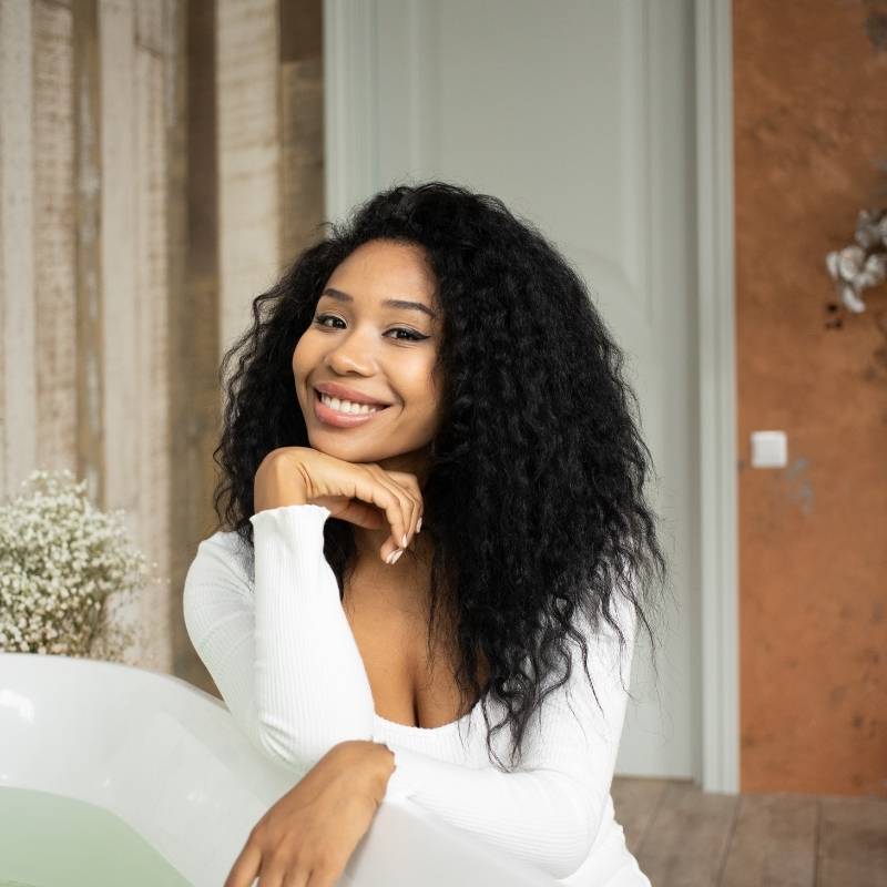smiling woman with natural makeup wearing a deep wave front lace wig